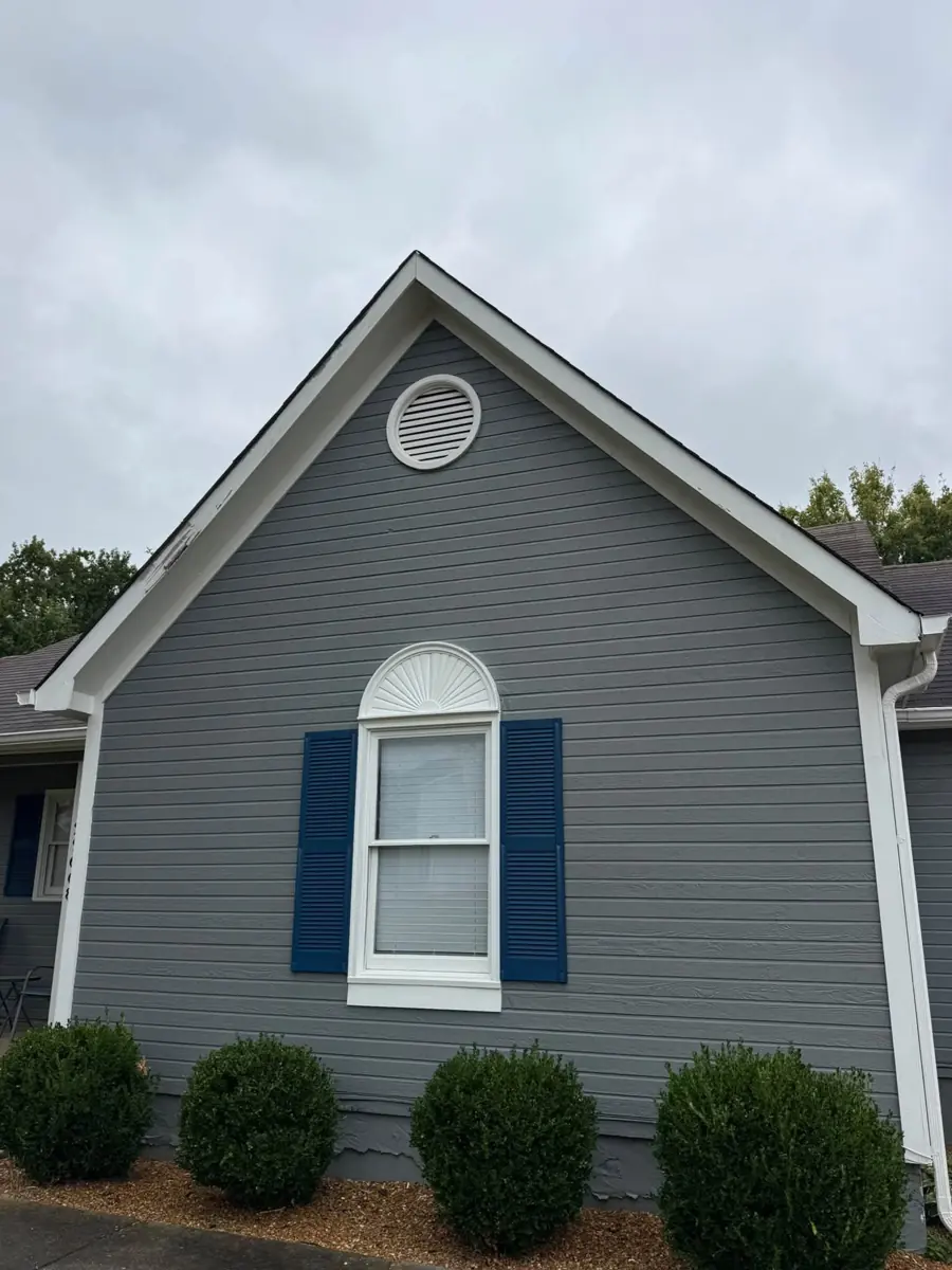 Freshly painted gray gable with white trim, arched window and navy shutters
